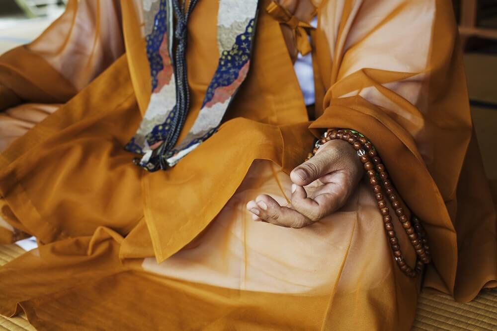 Tibetan monk in meditation pose with prayer beads