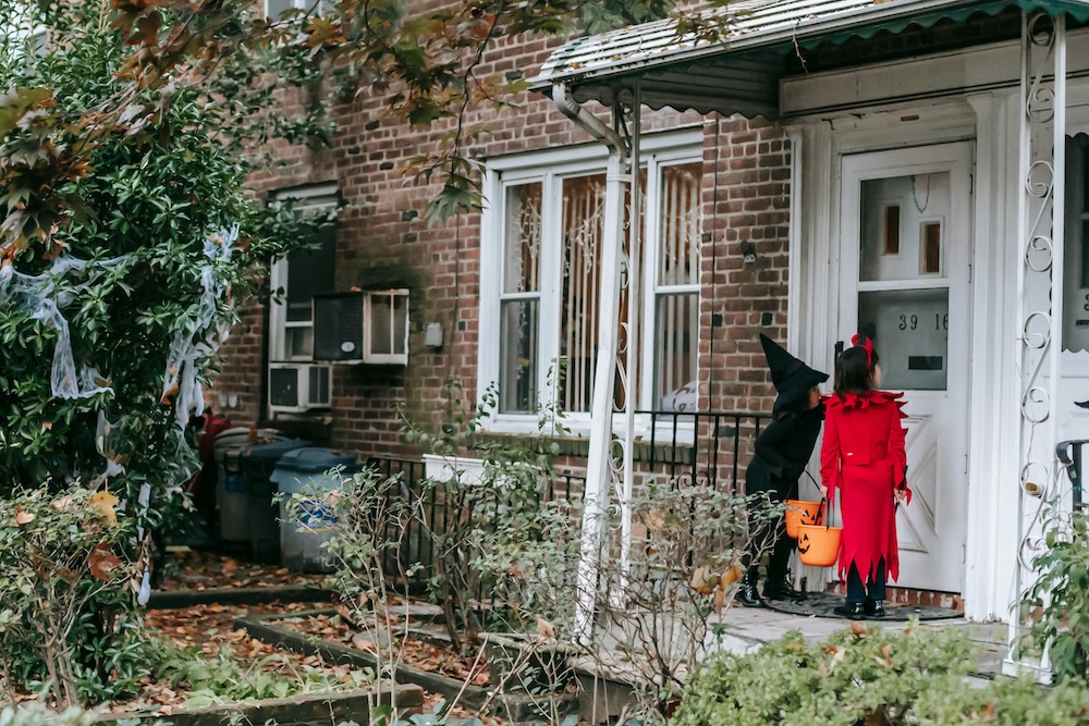Children in Halloween costumes trick-or-treating at a decorated house